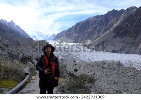 An Asian female tourist admiring the view of the large ice field at Passu Glacier on the Karakoram Highway in the northern part of Gilgit-Baltistan, Pakistan.
