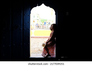 An Asian Female Tourist Standing At The Entrance Door Of A Historical Home Now Houses The Romantic Museum Museo Romántico In Plaza Mayor, Trinidad, Cuba.