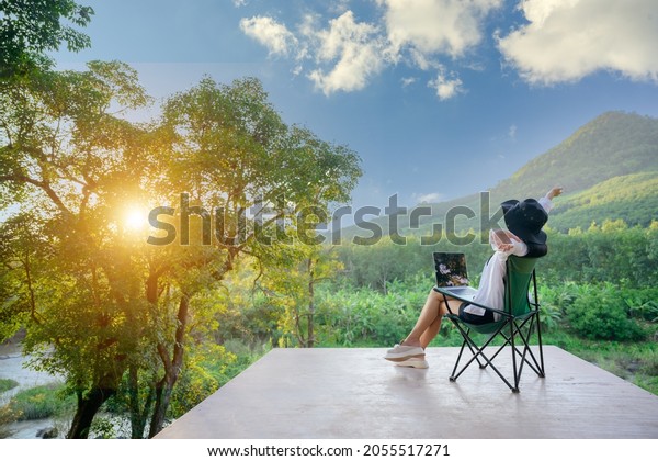 Asian\
female tourists wake up early to see the rising sun. Travel she\
likes to travel in style. beautiful nature forests and mountains\
work happy holidays with freelance work on\
laptop