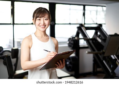 Asian female trainer standing with a smile in the training gym - Powered by Shutterstock