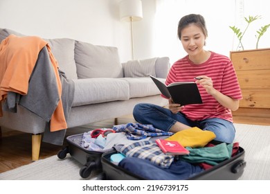 Asian Female Traveler Check Her List in a Note While Pack Her Suitcase Ready For Her Travel Vacation Trip - Shutterstock ID 2196739175
