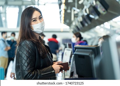 Asian Female Traveler Holding Passport At Customer Check In Of Airline Service Counter. New Normal, Woman Wearing Face Mask When Traveling By Airplane Transportation To Prevent Covid19 Virus Infection