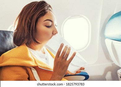 An Asian Female Traveler Suffers From An Acute Attack Of Nausea During Turbulence On A Plane. The Woman Was Seasick And Airsock During Air Flight