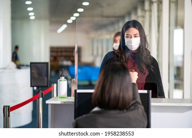 Asian female traveler wearing face mask giving passport to airline customer check in officer at airline service counter in airport. traveler wearing mask prevent covid-19 or coronavirus pandemic.