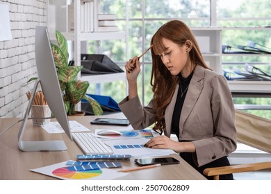 Asian female woman focused graphic designer analyzing color palettes and sketches in modern office workspace - Powered by Shutterstock