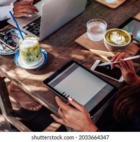 Asian Female Worker Uses Her Tablet And Pen Sitting At Table Outside