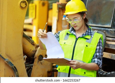 Asian female worker wear safety suits checking  of tracked excavator