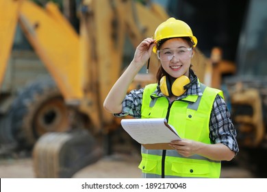 Asian female worker wear safety suits checking  of tracked excavator