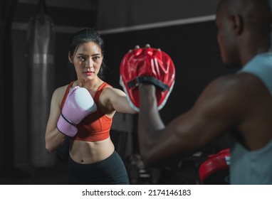 Asian fit female boxing training with her trainer at gym.Sportwoman  wearing boxing gloves exercise and punch to pads for boxing - Powered by Shutterstock