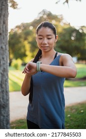 Asian Fitness Girl Checking Her Smart Watch To See Her Heartbeat After Jogging In The Park