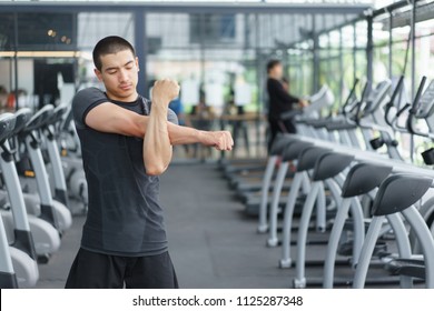 Asian fitness man warm up by stretching arms before exercises at the gym.  copy space.