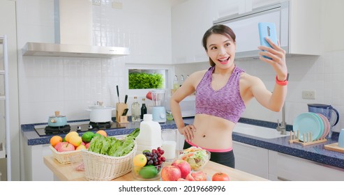 Asian Fitness Woman Taking Selfie While Standing In Kitchen At Home With Healthy Food