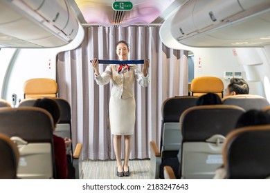 Asian Flight Attendant Is Demonstrating Safety Procedure Using Seat Belt Before Taking Off In The Airplane For Cabin Crew And Airline Business