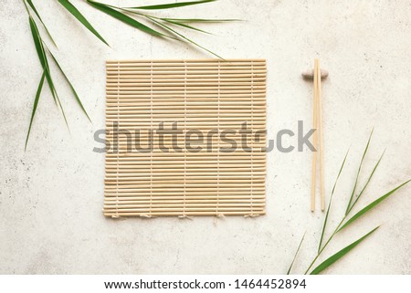 Asian food background - chopsticks, bamboo mat with bamboo leaves on light background. Asian menu design, chinese japanese cuisine concept. Foto d'archivio © 