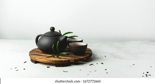 Asian food background with a tea set, cups, and teapot with free space for text on white stone background.
