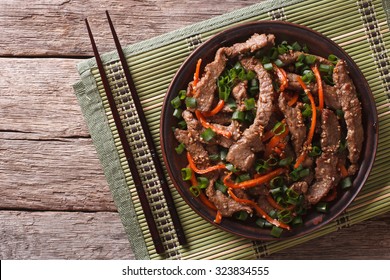 Asian Food: Bulgogi beef slices fried with sesame and carrot on a plate. Horizontal top view