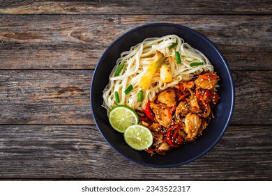 Asian food - chicken nuggets, noodles and stir fried vegetables on wooden table  - Powered by Shutterstock