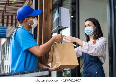 Asian Food Deliverly Man Wear Protective Mask Due To Covid-19 Pandemic, Show Online Order On Phone To Restaurant Worker At Coffee Shop. Waitress Give Takeaway Bag To Postman For New Normal Lifestyles.