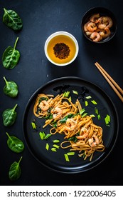 Asian Food - Noodles With Prawns In Soy Sauce With Spinach On Black Table