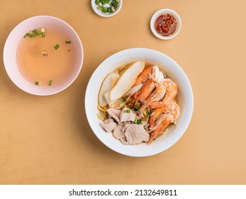 Asian Food Spicy Prawn Noodle In A Bowl With Soup, Chili Sauce And Spring Onion Top View On Wooden Table