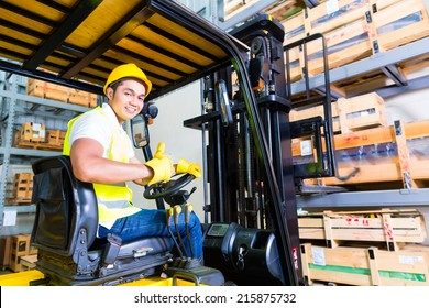 Asian fork lift truck driver lifting pallet in storage warehouse - Powered by Shutterstock