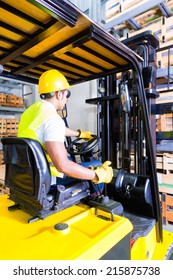 Asian Fork Lift Truck Driver Lifting Pallet In Storage Warehouse