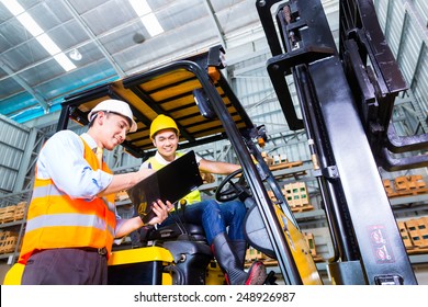 Asian Fork Lift Truck Driver Discussing Checklist With Foreman In Warehouse 