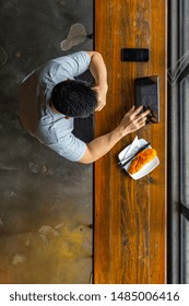Asian freelancer using tablet while having breakfast at cafeteria