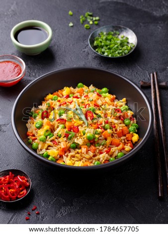 Asian fried rice with egg and vegetables. Dark stone background.