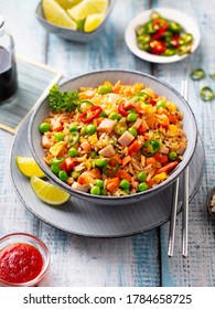 Asian fried rice with ham and vegetables. Blue wooden background. Close up.