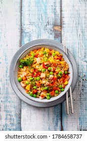 Asian fried rice with ham and vegetables. Blue wooden background. Top view.