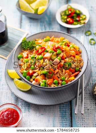Asian fried rice with ham and vegetables. Blue wooden background. Close up.