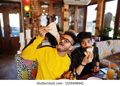 Asian Friends Guys Eating Pizza During Party At Pizzeria. Happy Indian People Having Fun Together, Eating Italian Food And Sitting On Couch.