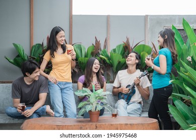 asian friends having fun singing and playing guitar together in the backyard - Shutterstock ID 1945975468