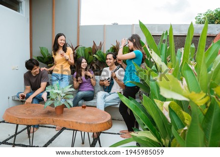 asian friends having fun singing and playing guitar together in the backyard