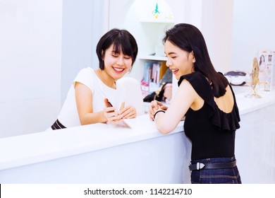 Asian front desk lobby receptionist talking and discussing with beautiful happy Asian female client