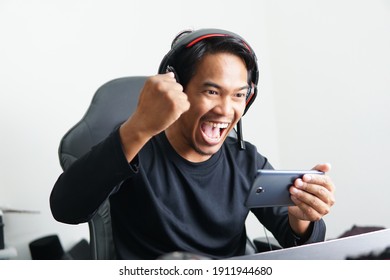 Asian Gamer playing mobile game with excited expression emotion. Winning esport game