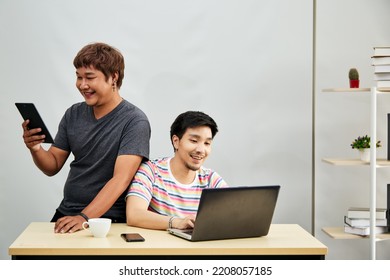 Asian Gay Couple At Office Using Internet Through Digital Tablet And Laptop Online Searching Shopping Communication