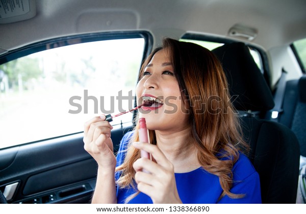 asian girl applying make\
up in the car