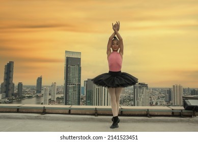 Asian girl in a ballet costume dances ballet on the rooftop of a high-rise building.  - Powered by Shutterstock