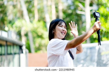asian girl Beautiful, smiling broadly, standing at home and enjoying a light selfie. with a compact camera on a blurred background - Shutterstock ID 2211980945