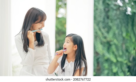Asian girl brushing her teeth with mom. Dental care. Oral care. - Shutterstock ID 2082767722