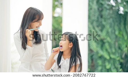 Asian girl brushing her teeth with mom. Dental care. Oral care.