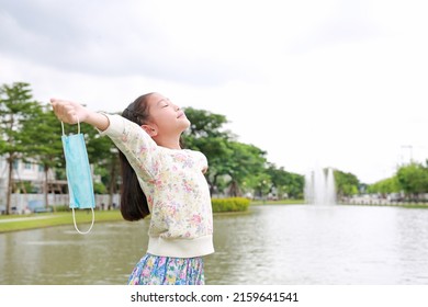 Asian girl child relax and breathing deep fresh air relieving taking off mask due covid-19 on the garden. - Shutterstock ID 2159641541