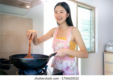 Asian Girl Cooking A Fried Chicken By A Pan In Her Kitchen