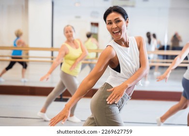 Asian girl dancing modern dance in fitness studio with other dancers - Powered by Shutterstock