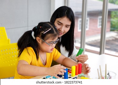 Asian girl with Down's syndrome play puzzle toy with her teacher in classroom. - Shutterstock ID 1822373741