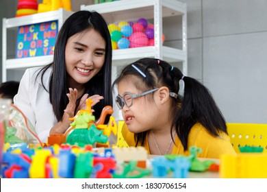 Asian girl with Down's syndrome play toy with her teacher in classroom. Concept disabled kid learning. - Shutterstock ID 1830706154