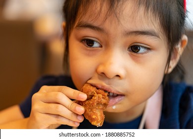 Asian Girl Eating Chicken. Child Eating A Chicken Nuggets