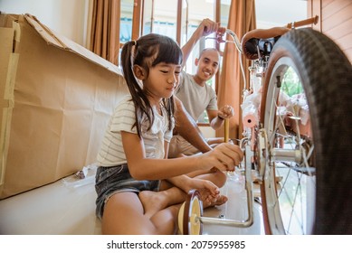 Asian Girl Fixing Bolts With Dad On Her New Bike